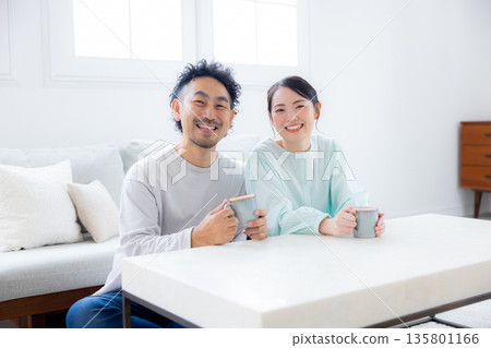 一對夫婦在客廳看智慧型手機 一對夫婦在客廳看智慧型手機 135801166
