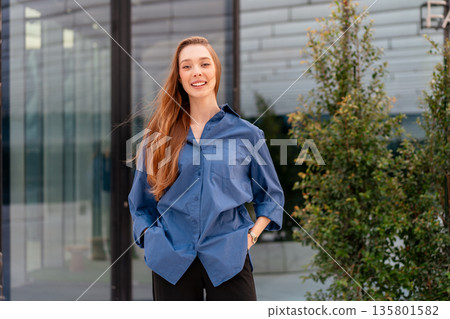Confident businesswoman smiling near modern glass Confident businesswoman smiling near modern glass 135801582
