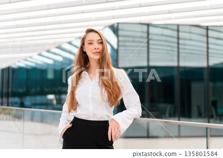 Confident young businesswoman standing near modern 135801584