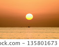 A sinking sun and a ship sailing directly below it 135801673