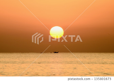 A sinking sun and a ship sailing directly below it 135801673