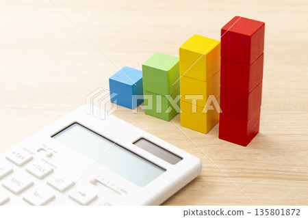 A calculator and a building block graph on a desk 135801872