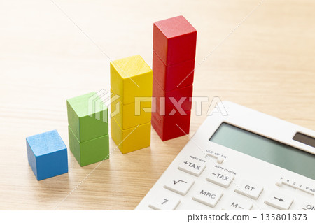 A calculator and a building block graph on a desk 135801873