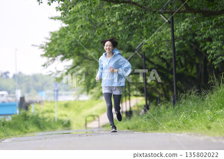 A woman in her 40s running outdoors A woman in her 40s running outdoors 135802022
