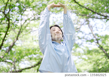 A woman in her 40s doing warm-up exercises outdoors 135802025