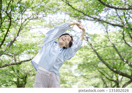 A woman in her 40s doing warm-up exercises outdoors A woman in her 40s doing warm-up exercises outdoors 135802026