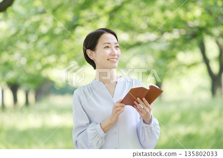 Woman reading outdoors 135802033