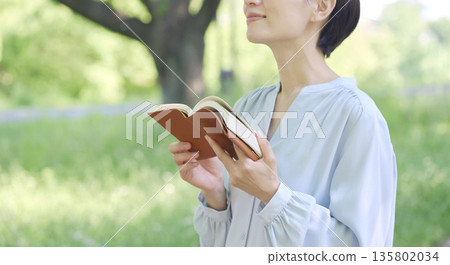 Woman reading outdoors, faceless 135802034
