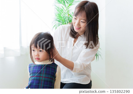 Mother tying girl's hair Mother tying girl's hair 135802290