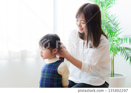 Mother tying girl's hair 135802297