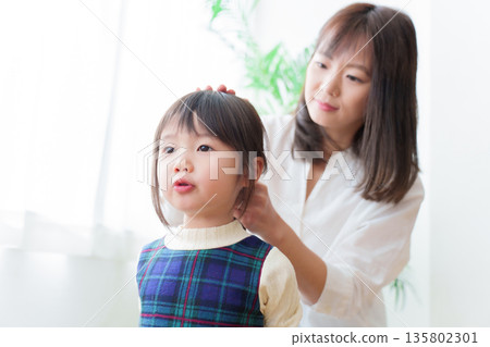 Mother tying girl's hair Mother tying girl's hair 135802301