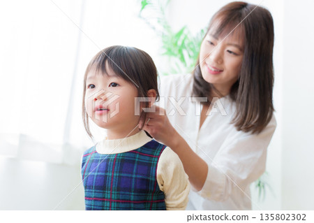 母親正在幫女兒綁頭髮 母親正在幫女兒綁頭髮 135802302