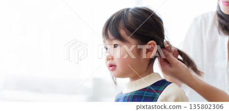 Mother tying girl's hair Mother tying girl's hair 135802306