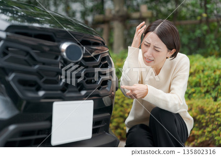 A woman crouches on the road after crashing her car 135802316