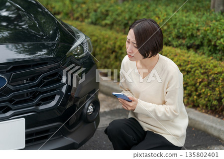 一名女子因汽車故障而操作智慧型手機 135802401