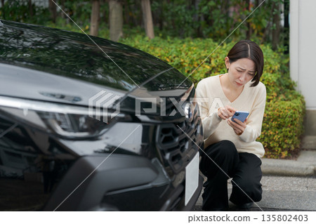 一名女子因汽車故障而操作智慧型手機 135802403