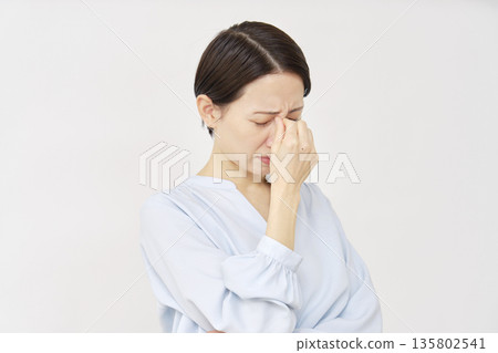 Woman in her 40s, eyestrain, white background Woman in her 40s, eyestrain, white background 135802541