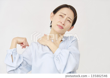 Woman in her 40s with stiff shoulders, white background 135802546