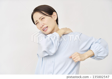 Woman in her 40s with stiff shoulders, white background Woman in her 40s with stiff shoulders, white background 135802547