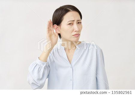 Hearing-impaired woman in her 40s on white background Hearing-impaired woman in her 40s on white background 135802561