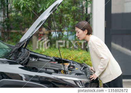 汽車拋錨後，一名女子打開了引擎蓋。 135802672