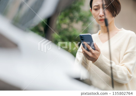 一位汽車拋錨的女士透過電話聯繫了某人。 135802764