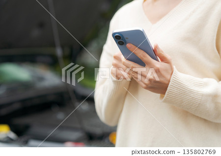 一名女子在車前操作智慧型手機 135802769