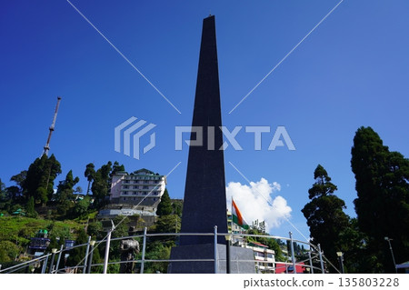 Tall black granite obelisk war memorial standing under a clear blue sky at Batasia Loop in Darjeeling India Tall black granite obelisk war memorial standing under a clear blue sky at Batasia Loop in Darjeeling India 135803228
