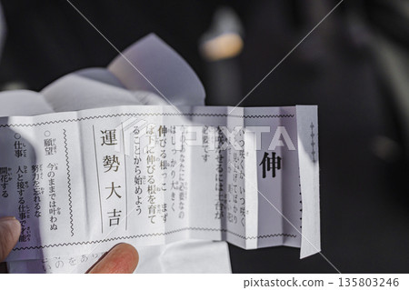 Nishiarai Daishi Temple: Close-up of hands opening a lucky fortune slip Nishiarai Daishi Temple: Close-up of hands opening a lucky fortune slip 135803246