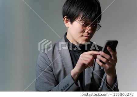 A suspicious man looking at his smartphone 135803273