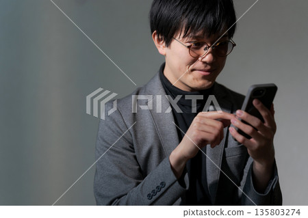 A suspicious man looking at his smartphone A suspicious man looking at his smartphone 135803274