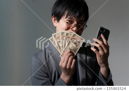 Suspicious man holding smartphone and money 135803524