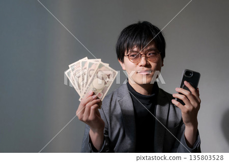 可疑男子手持智慧型手機和現金 135803528