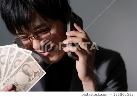 可疑男子手持智慧型手機和現金 135803532