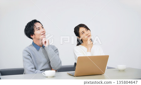 A couple thinking while looking at a laptop in a room 135804647