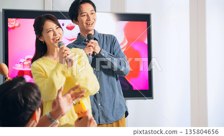 A group of men and women singing in a karaoke box A group of men and women singing in a karaoke box 135804656