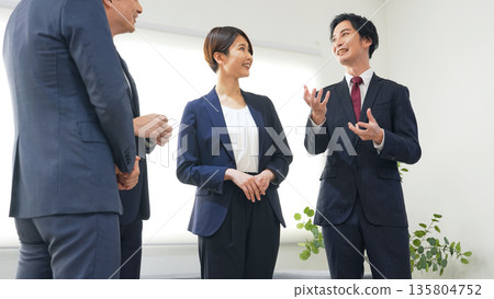 一群商務人士站在辦公室交談。 一群商務人士站在辦公室交談。 135804752