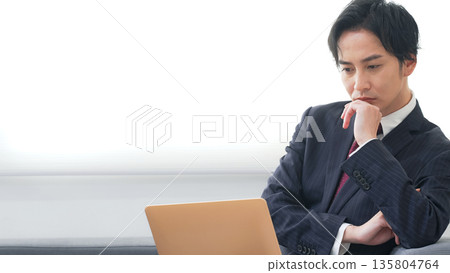 Male business person using a laptop in the office 135804764