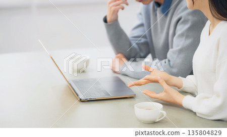 一對夫婦在房間裡看筆記型電腦。 135804829