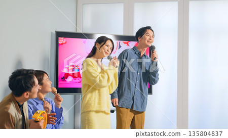 A group of men and women singing in a karaoke box 135804837