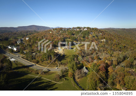View from above of expensive residential houses high on hill top between yellow fall trees in suburban area in North Carolina. American dream homes as example of real estate development in US suburbs 135804895
