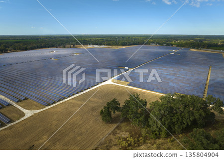 Aerial view of large sustainable electrical power plant with rows of solar photovoltaic panels for producing clean electric energy. Concept of renewable electricity with zero emission Aerial view of large sustainable electrical power plant with rows of solar photovoltaic panels for producing clean electric energy. Concept of renewable electricity with zero emission 135804904