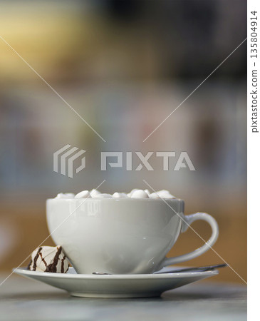 Mug of coffee with marshmallows on porcelain plate on blurred colorful interior bokeh background. 135804914