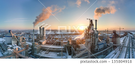 Aerial view of cement factory tower with high concrete plant structure at industrial production area at sunset. Manufacturing and global industry concept Aerial view of cement factory tower with high concrete plant structure at industrial production area at sunset. Manufacturing and global industry concept 135804918