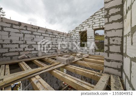 Interior of future cottage, energy saving walls and chimney of large white hollow foam insulation on blue sky and woody hills copy space background. Construction, masonry, modern technology concept. 135804952
