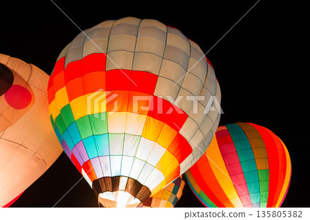 colorful hot air balloons glowing against dark night sky colorful hot air balloons glowing against dark night sky 135805382