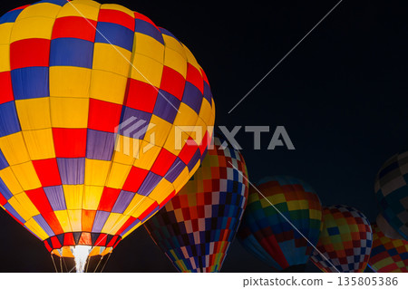 colorful hot air balloons glowing against dark night sky 135805386