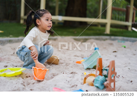 happy child girl playing sand with toy on playground 135805520