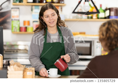 Barista girl serves customer, pours coffee into cup, fills cup with fragrant coffee. Barista girl serves customer, pours coffee into cup, fills cup with fragrant coffee. 135805729