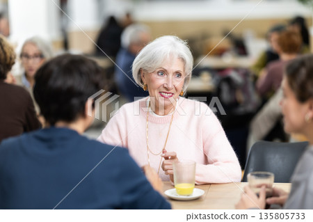 Pleasant positive elderly woman meeting and chatting with family in cozy cafeteria Pleasant positive elderly woman meeting and chatting with family in cozy cafeteria 135805733